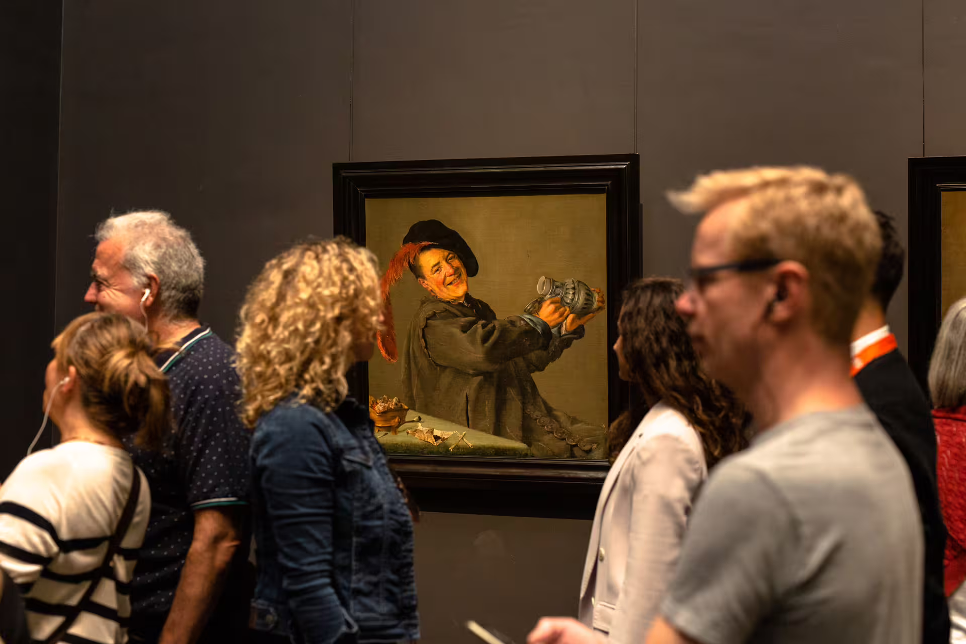 Visitors engage with classic art during a private guided tour at the Rijksmuseum, showcasing a painting by Frans Hals.