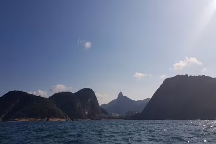 Panoramic view of Rio's iconic Sugarloaf Mountain from a boat with clear blue skies and calm waters.