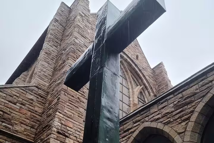 Close-up of a large cross statue outside a historic stone building on Robben Island, part of the guided tour.