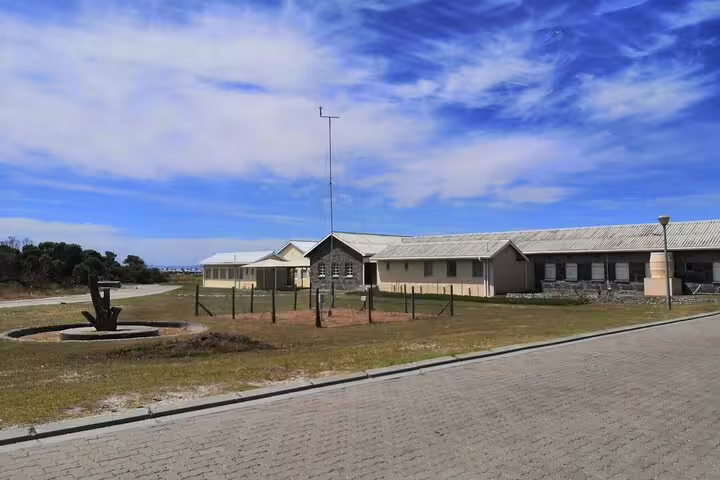 Scenic view of Robben Island's historic buildings under a blue sky, part of the guided museum tour experience.