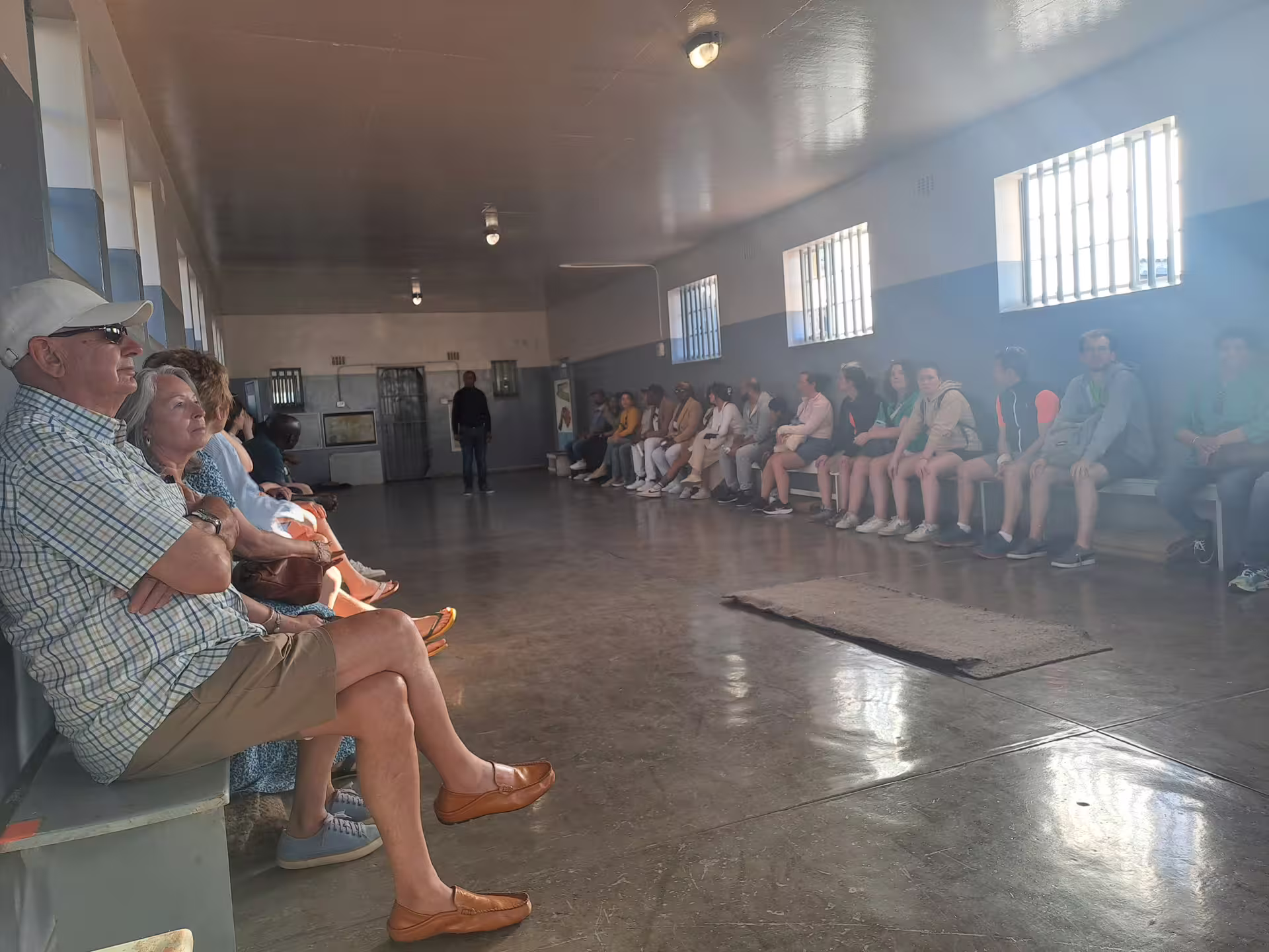 Tourists seated inside a historic building at Robben Island Museum, part of a guided ferry tour experience.