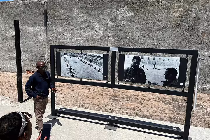 Tour guide explains historic photos at Robben Island Museum on guided tour, highlighting apartheid history.
