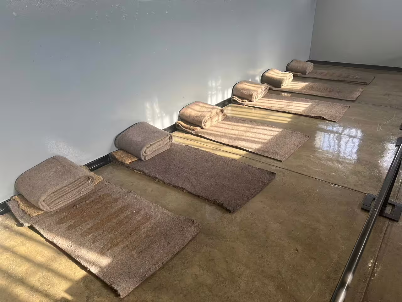 Simple sleeping mats and blankets in a Robben Island Museum cell, highlighting historical prison conditions.