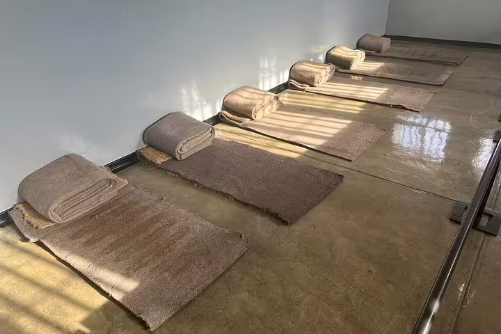 Sparse sleeping arrangements in a Robben Island prison cell, showcasing historical conditions on the guided tour.