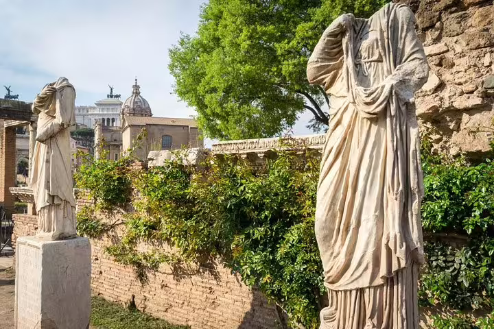 Ancient headless marble statues and ivy-covered walls in the Roman Forum on a private Colosseum and Forum guided tour in Rome
