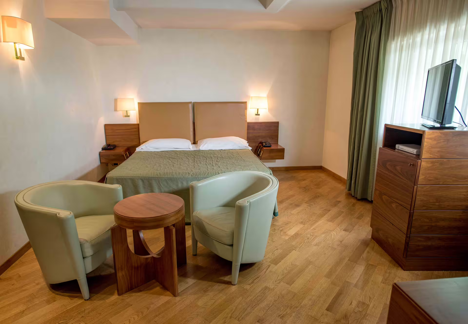 Bright, modern double room in Solofra hotel with cozy seating area, hardwood floors and soft lighting for romantic stays