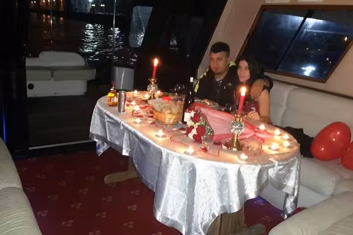 Romantic private yacht anniversary dinner with candlelit table, roses and city lights on the water
