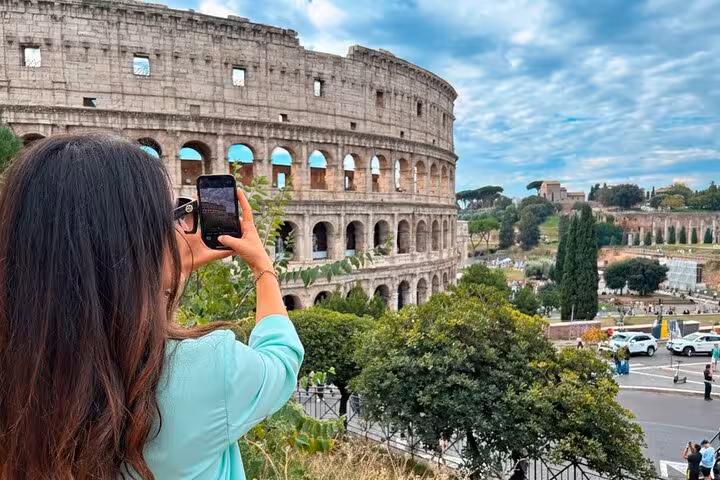 Visitor photographing the iconic Colosseum in Rome, perfect for a tour featuring pizza and gelato making.