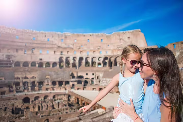 Mother and daughter enjoying a private guided tour with panoramic view of the Rome Colosseum arena under a bright blue sky