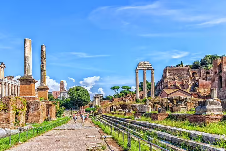 Ancient columns and pathways of the Roman Forum under blue skies, explored on a Rome Colosseum Arena and Forum private guided tour