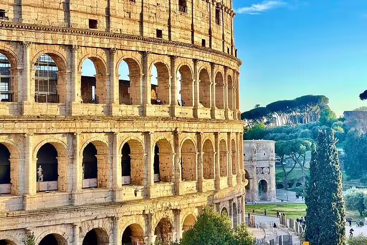 Close-up of the Colosseum arches at sunrise with surrounding park, included in Rome two days private chauffeured skip-the-line tour