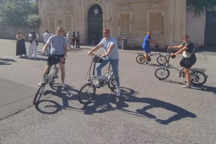Group enjoying a Rome e-bicycle tour in front of an ornate historic building, perfect for exploring city highlights.