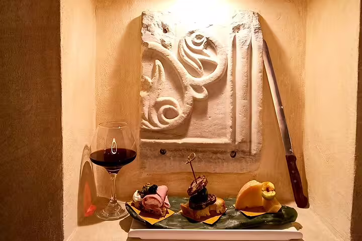 Gourmet appetizers and Italian red wine from the Fabullus tasting menu displayed in an elegant Rome wine cellar niche