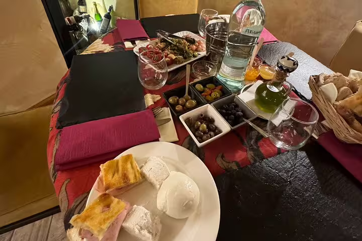 Gourmet Fabullus menu spread in a cozy Rome wine bar with fresh mozzarella, focaccia, olives and Italian antipasti.