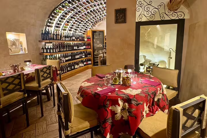 Cozy Rome restaurant dining room with arched wine cellar wall, set tables and warm lighting for Fabullus menu with wine pairing