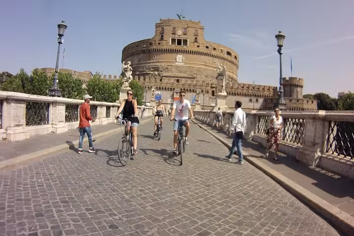 Cyclists explore Castel Sant'Angelo on a guided Rome Highlights by E-Bicycle tour, enjoying a sunny day.