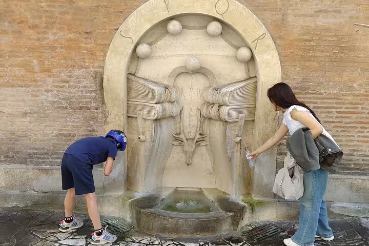Visitors filling water bottles at a historic fountain on the Rome Highlights by E-Bicycle small group tour.