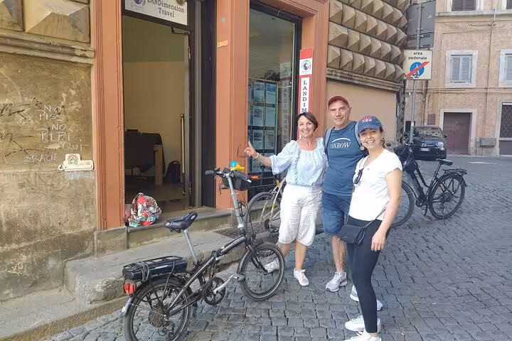 Smiling group ready for Rome Highlights E-Bicycle tour on a charming cobblestone street.