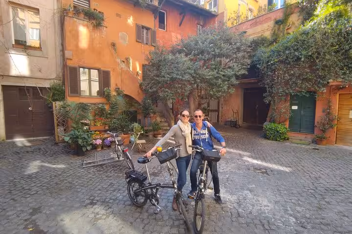 Two cyclists explore a picturesque courtyard in Rome on an E-Bike tour.