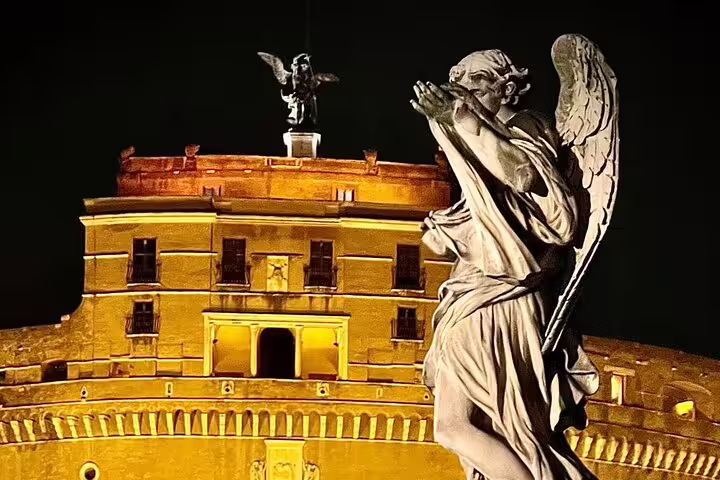 Angel statue on Ponte Sant’Angelo facing the glowing Castel Sant’Angelo during a Rome by night private car tour