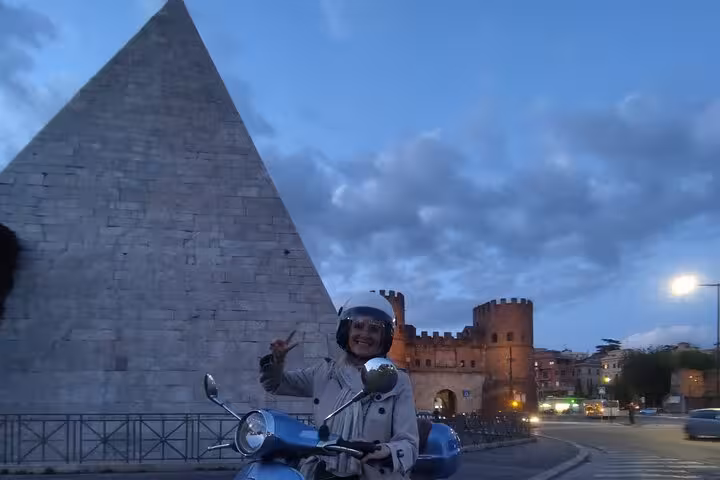 Explore Rome's historic landmarks on a Vespa at night, featuring the iconic Pyramid of Cestius.