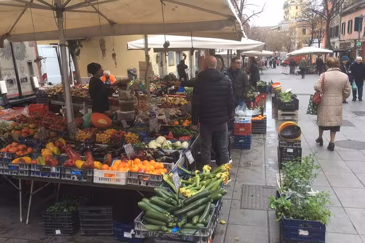 Bustling Pigneto street market in Rome with diverse fruits and vegetables on display for visitors.