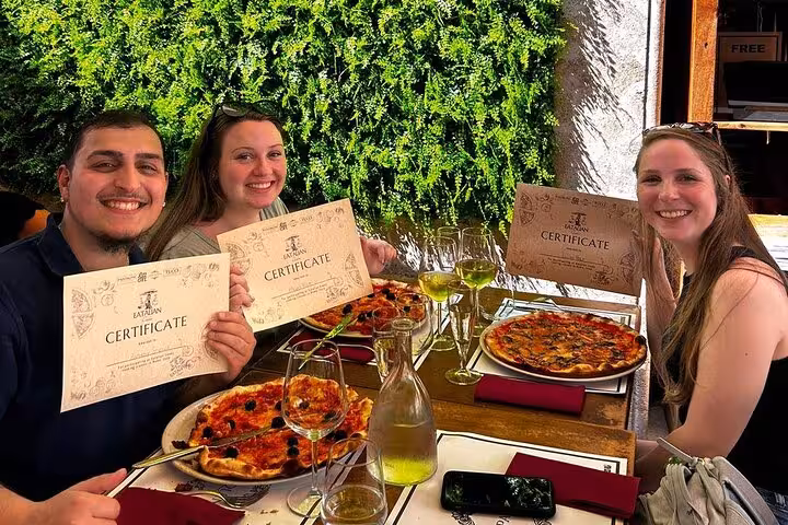 Happy participants holding certificates in a Rome pizza cooking class near Piazza Navona.