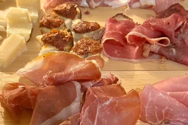 Close-up of Italian prosciutto, cured meats and cheese bites served on a rustic wooden board in a Rome wine pairing tour