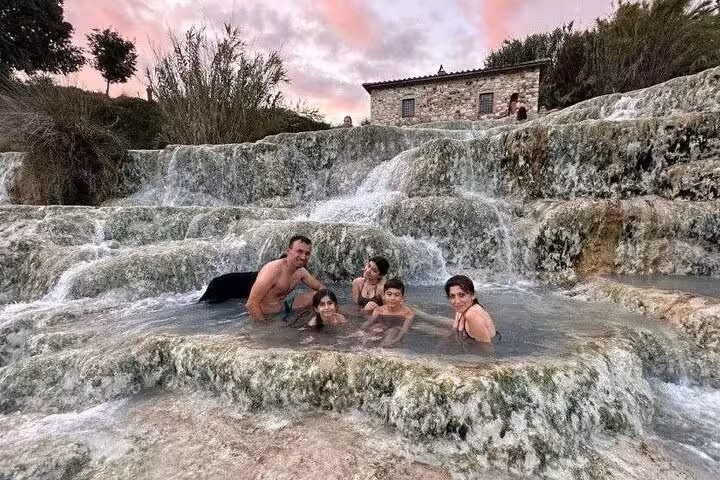 Family enjoying the natural thermal pools at Terme di Saturnia during a scenic sunset in Italy.