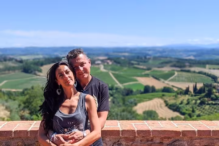 Couple enjoying a scenic view of Tuscany's vineyards on a day trip from Rome with wine tasting included.