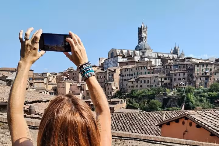 Traveler capturing Siena's historic skyline on a day trip from Rome, highlighting Tuscany's charm.