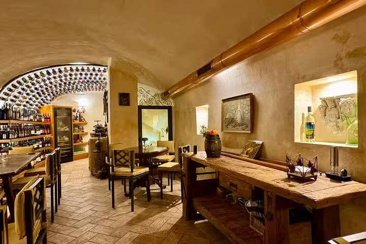 Cozy Roman wine cellar with rustic tables and bottles lining the arched ceiling, featured on a private food and wine tour