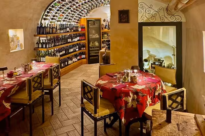 Cozy Rome wine cellar restaurant with arched bottle-lined walls, intimate tables and gourmet tasting setup for private tour guests