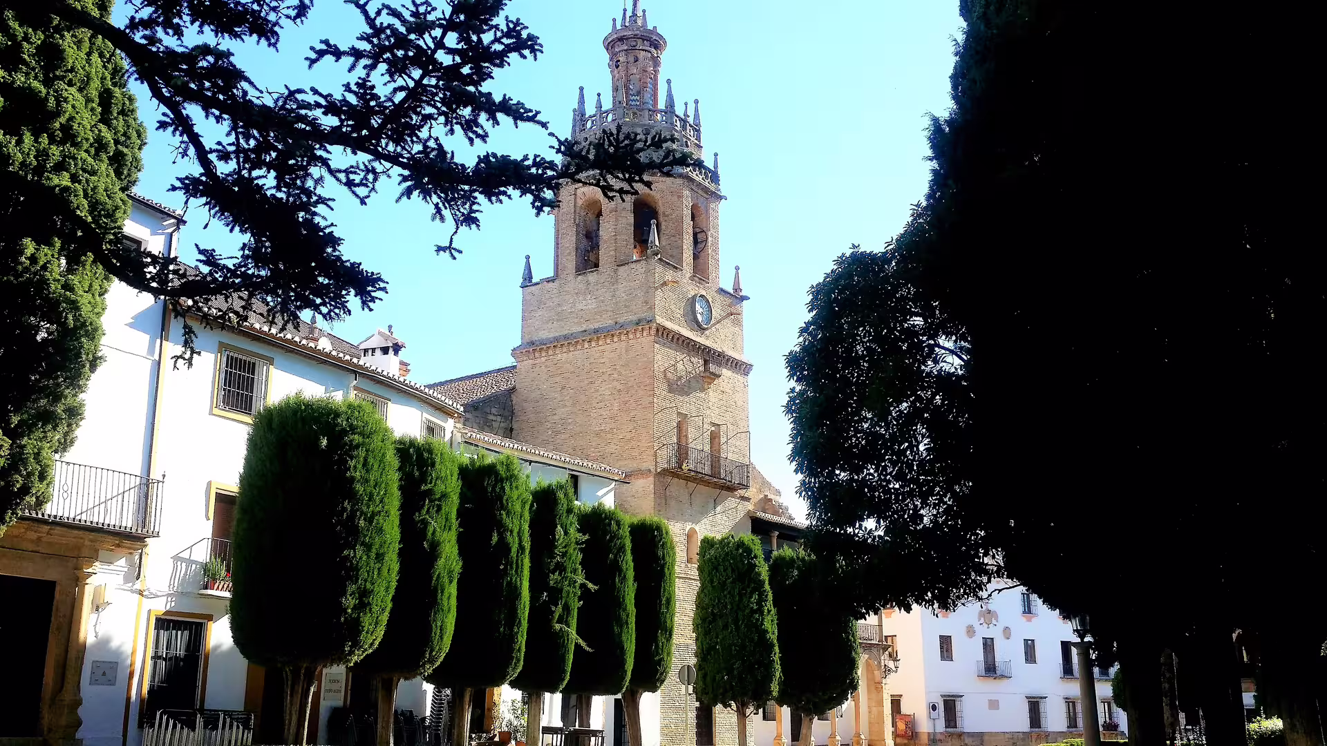 Ronda’s Iglesia del Espíritu Santo clock tower framed by cypress trees on a small-group guided walking tour