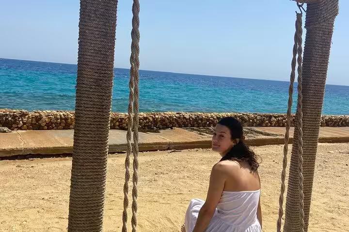 Traveler on a rope swing facing the Red Sea at Ain El Sokhna, relaxing stop on a day tour from Cairo