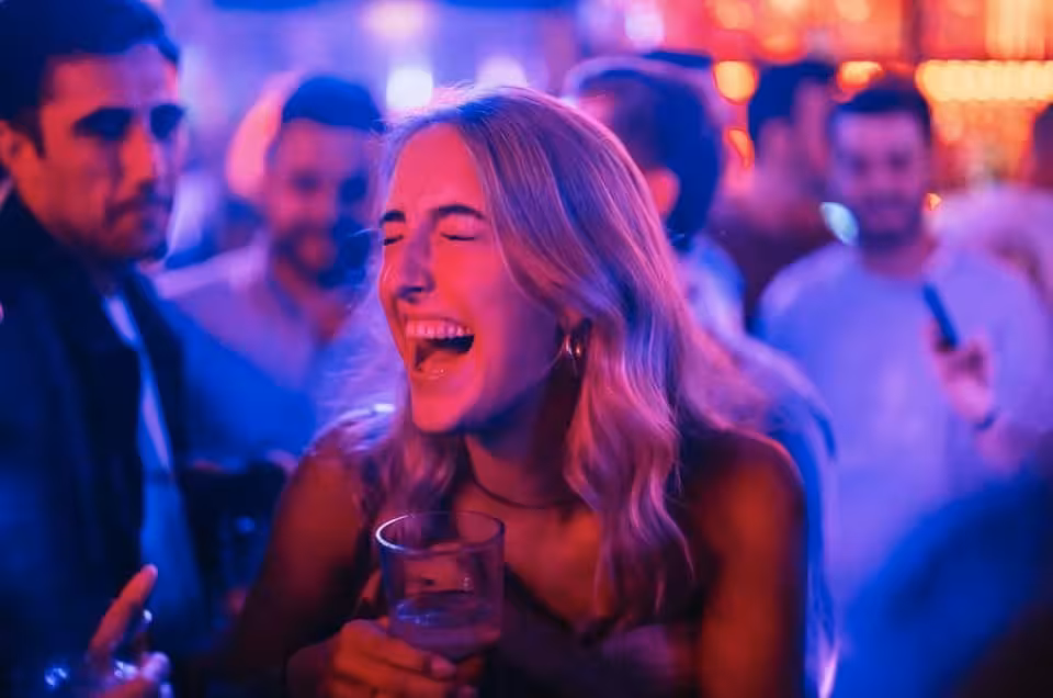 Partygoer laughing with drink under neon lights on Ludwig’s Rotterdam private pub crawl with VIP club entry