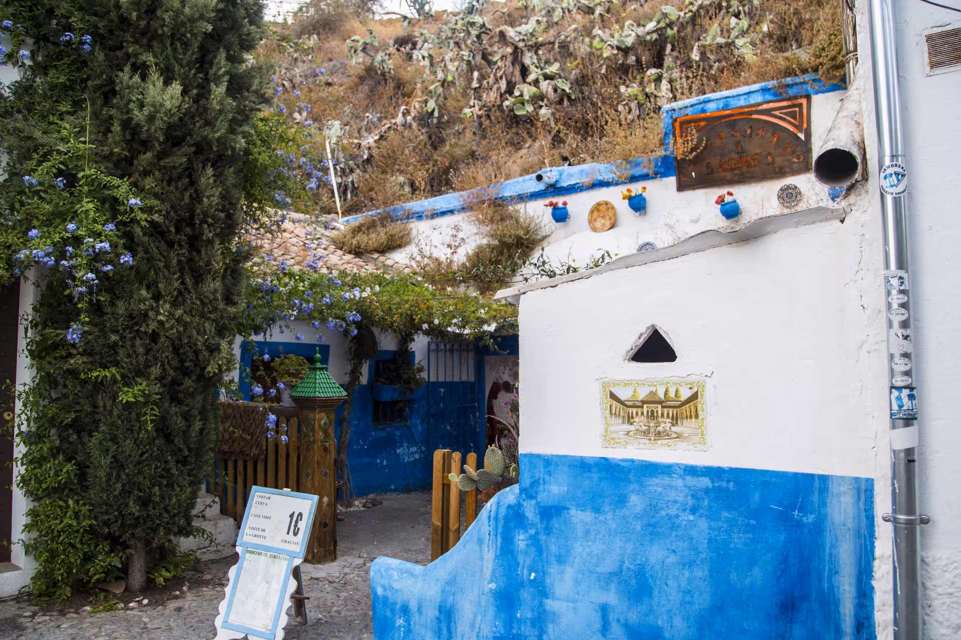 Charming blue and white house adorned with vibrant flowers in the historic Sacromonte neighborhood of Granada.