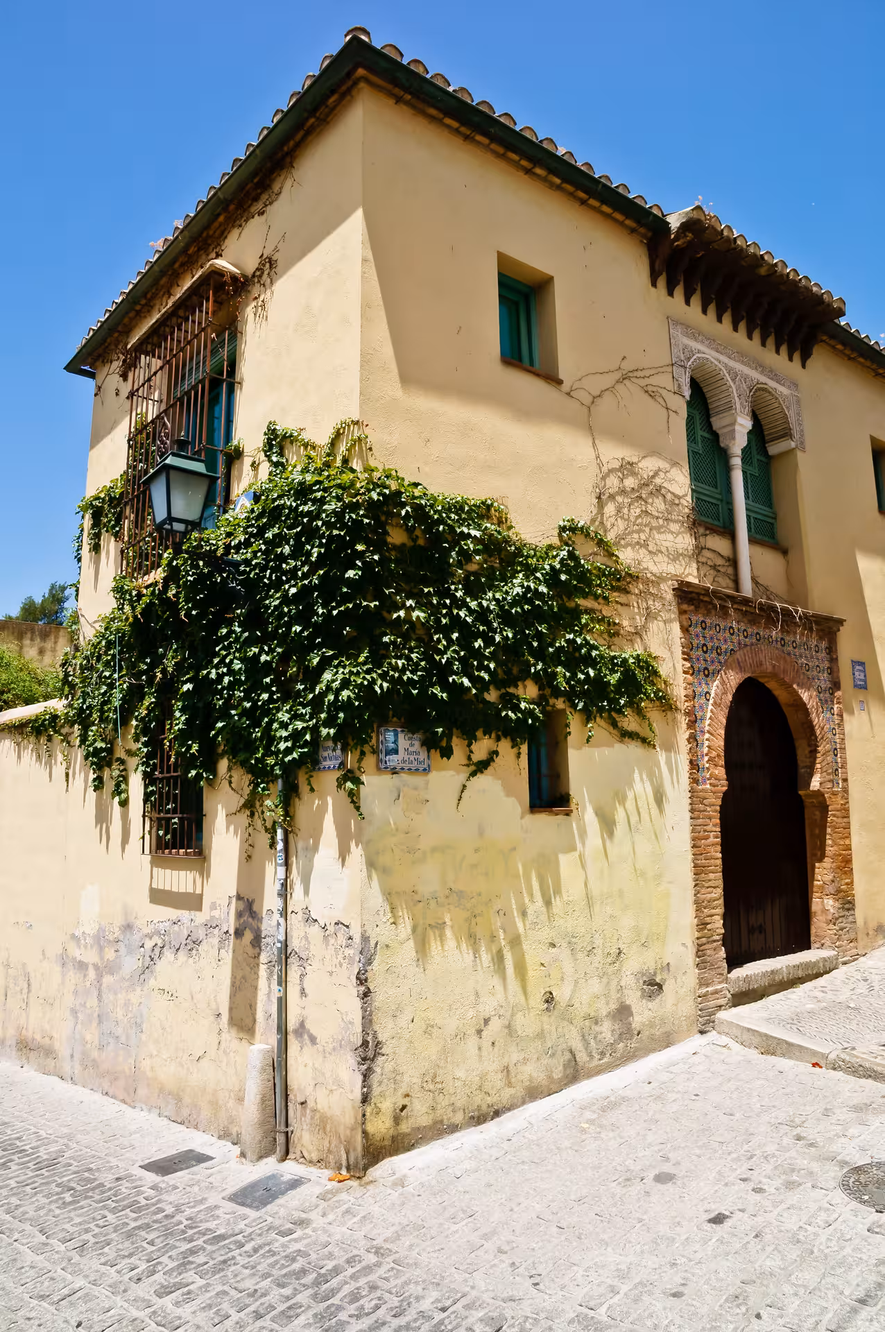 Historic building in Sacromonte, Granada, with ivy climbing its walls and a beautifully detailed arched entrance.