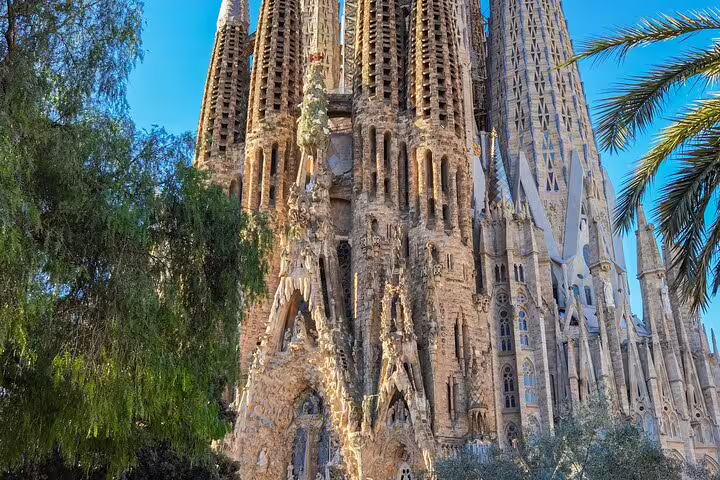 Exterior view of Sagrada Familia’s iconic spires amidst greenery, emphasizing the grandeur of this skip-the-line tour.