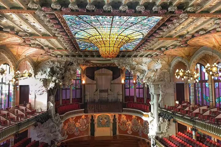 Stunning interior of Palau de la Música Catalana with intricate stained glass ceiling, featured on the Sagrada Familia Gaudi tour.
