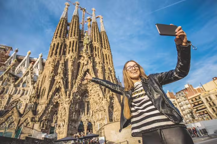 Woman taking a selfie in front of Sagrada Familia during a private Gaudi tour with skip-the-line tickets in Barcelona.