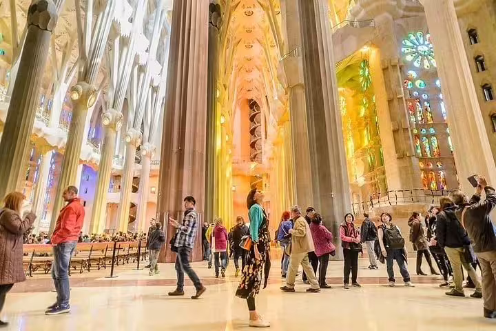 Visitors admiring the stunning interior of Sagrada Familia, with its towering columns and vibrant stained glass windows.