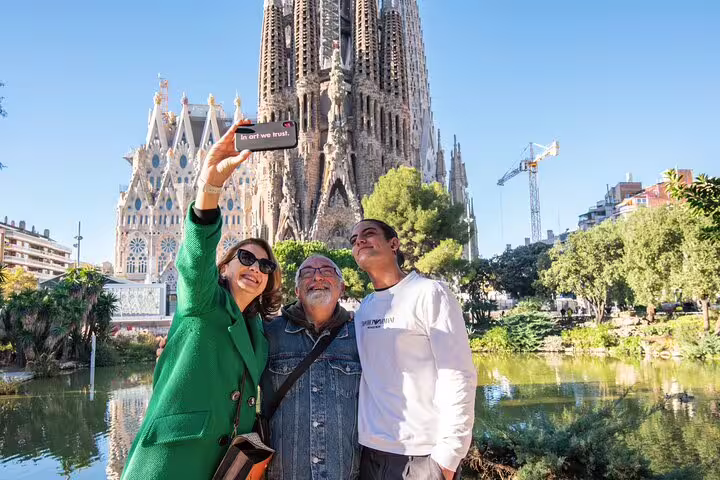 Tourists taking selfies in front of the iconic Sagrada Familia during a private guided tour with skip-the-line access.