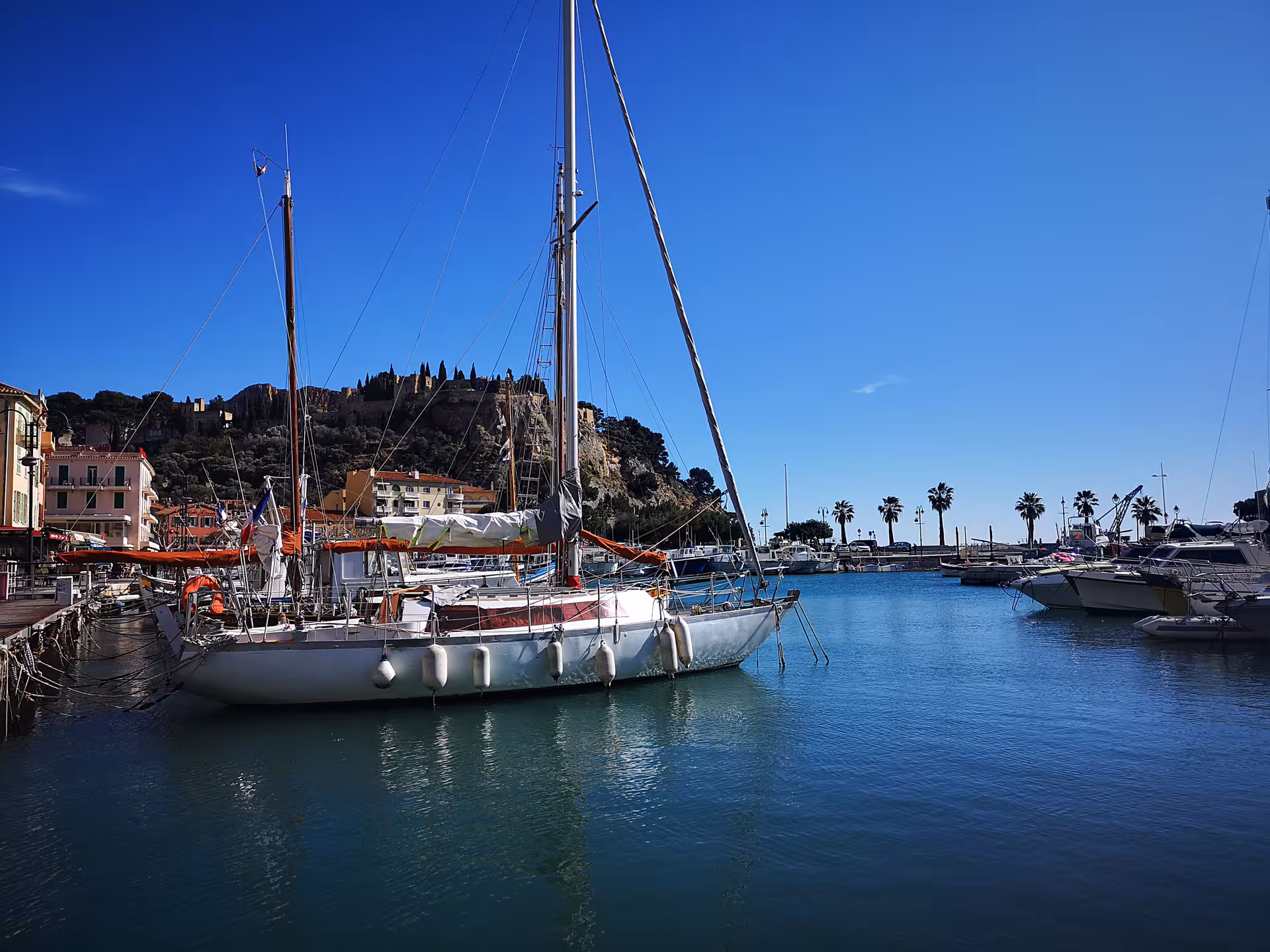 Sailboat moored in Cassis marina with hillside views, part of a private day tour from Marseille and Le Castellet