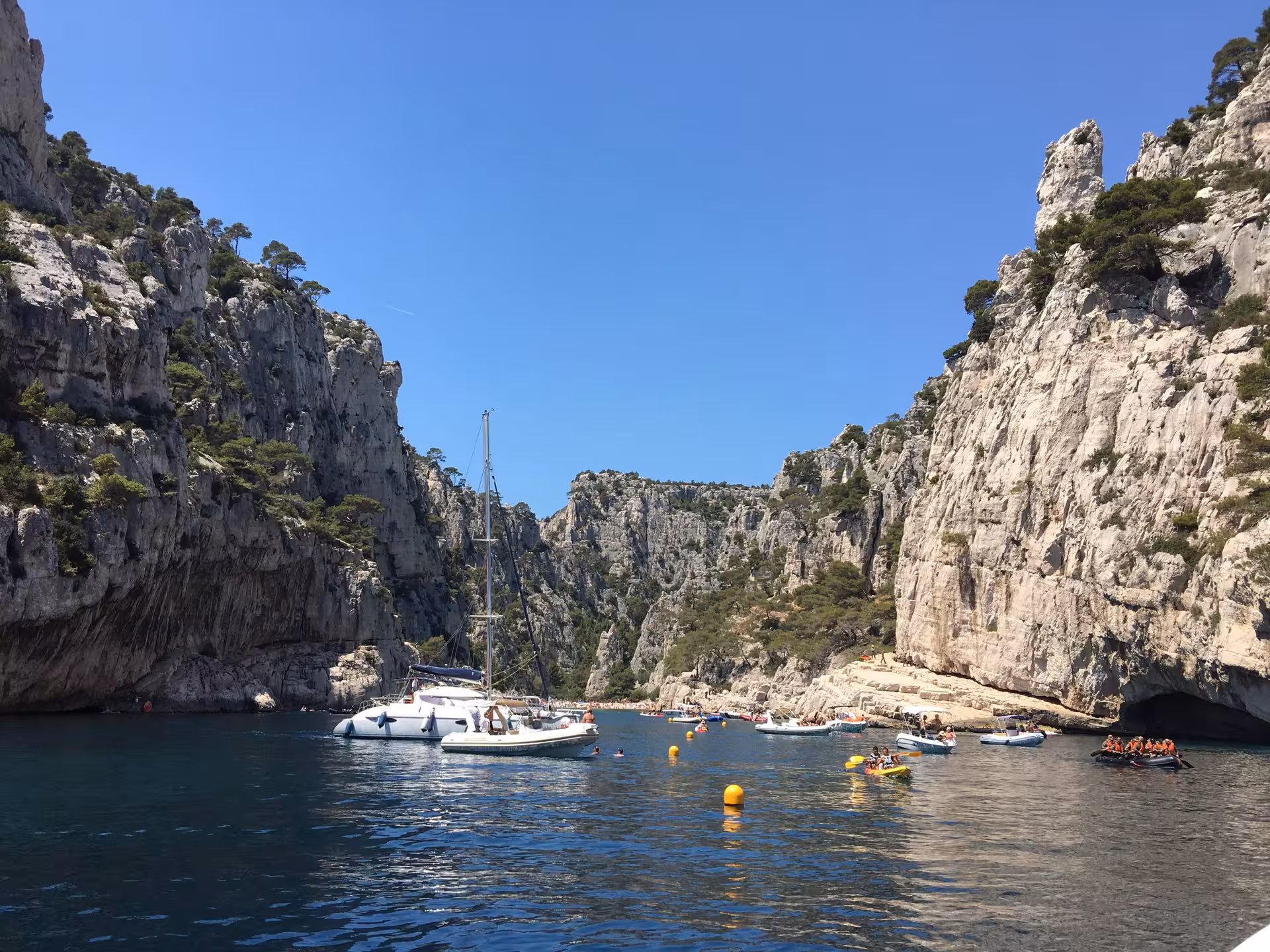 Sailboats anchored in a Mediterranean cove with limestone cliffs, perfect for 3-day boating and snorkeling tour