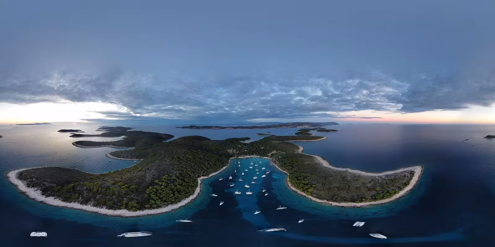 Panoramic sunset over an island marina with sailboats in a calm bay, scenic sailing adventure island hopping