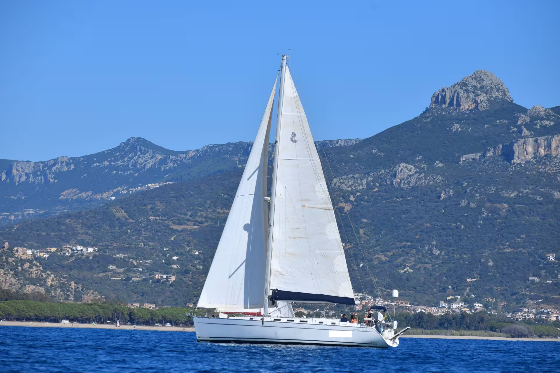 Sailing boat gliding through the Gulf of Orosei with rugged Sardinian mountains in the background, perfect for tours.