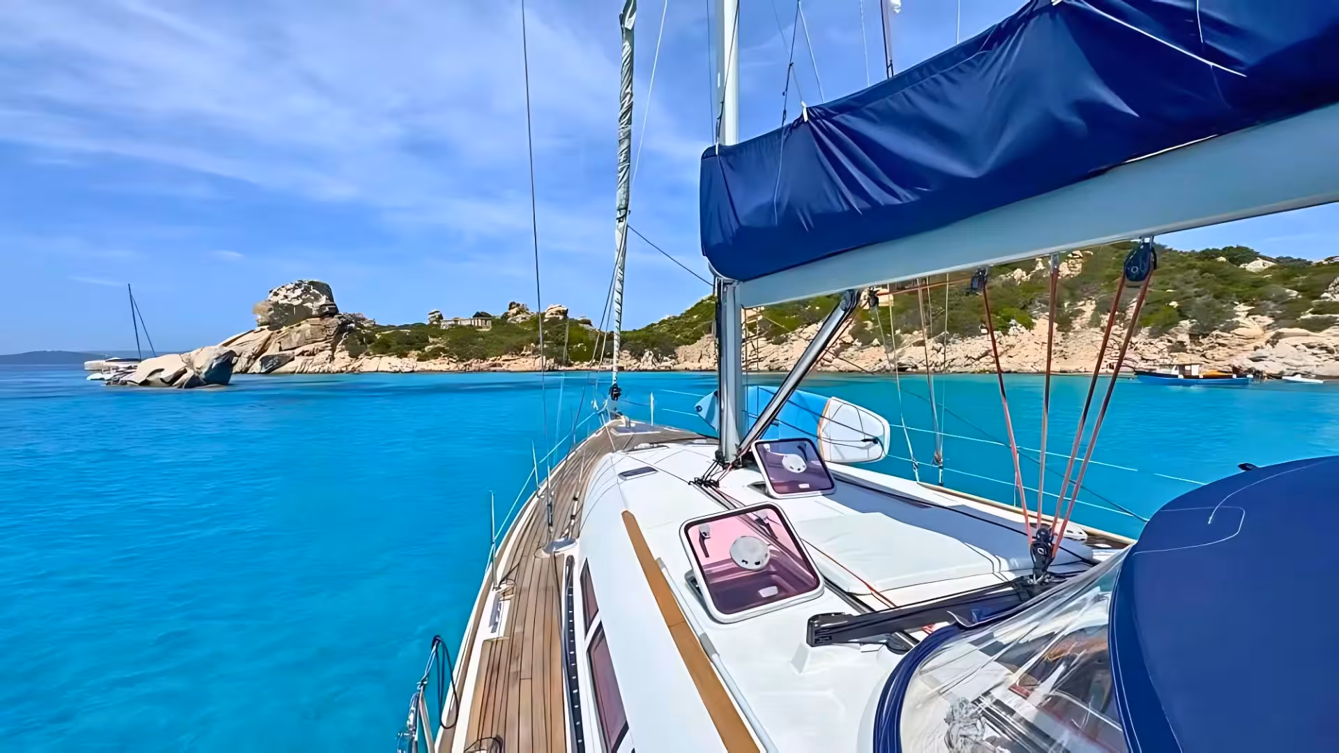 Sailing boat cruising through the crystal-clear turquoise waters of La Maddalena Archipelago, highlighting scenic beauty.