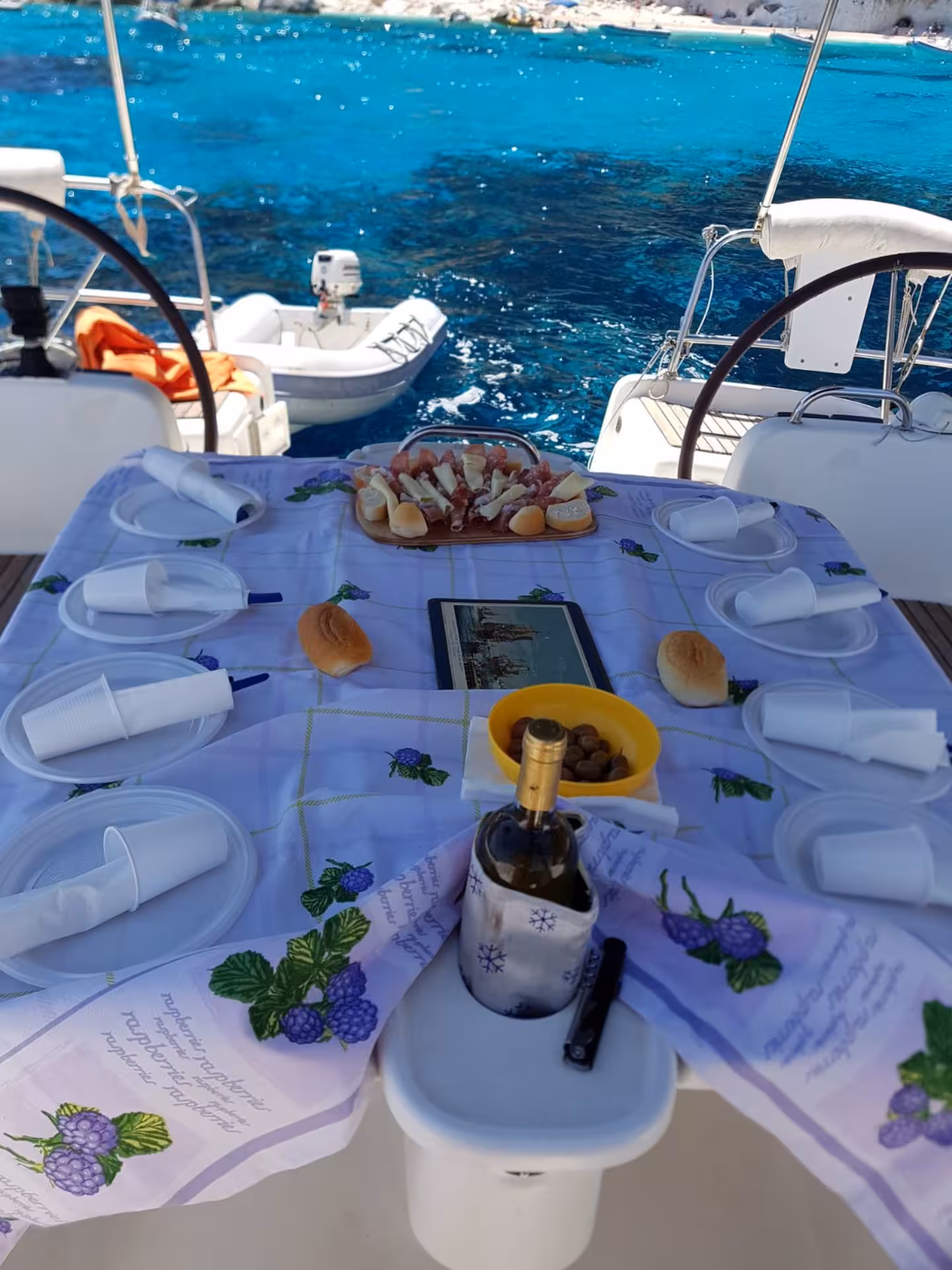 Lunch setup on a sailing boat with wine and local delicacies, overlooking the turquoise waters of the Gulf of Orosei.