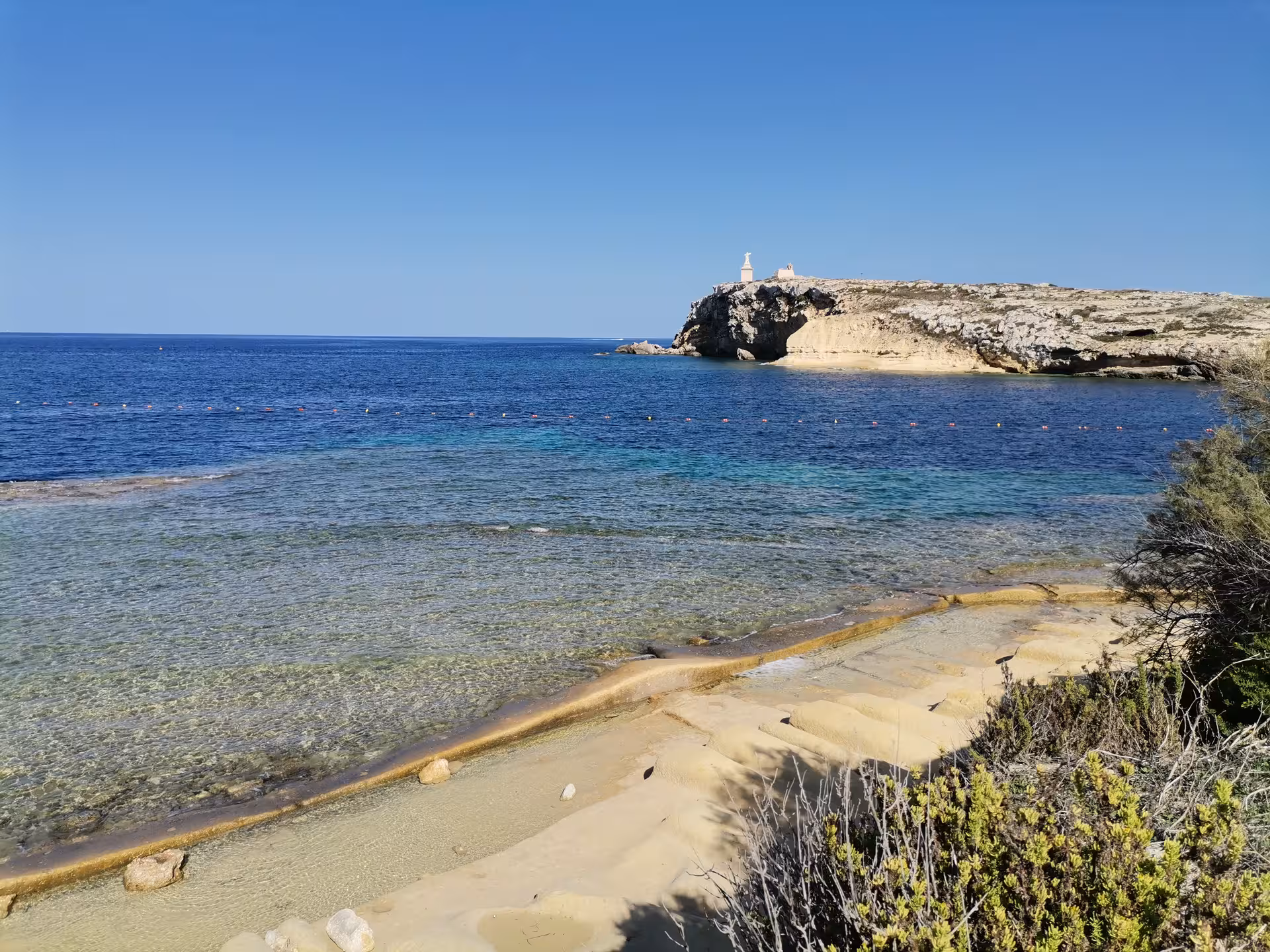 Crystal-clear bay and rocky headland on Saint Pauls Bay hiking tour, perfect stop for a local picnic in Malta